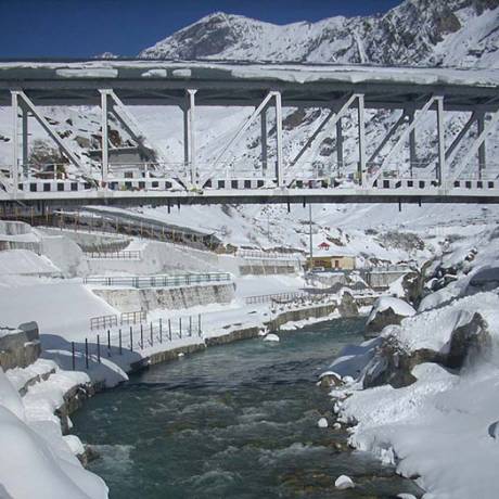 view of a snow covered bridge over Alaknanda river, flowing through Badrinath town.