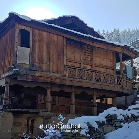 An old wooden house of Sankri village and snowy streets.